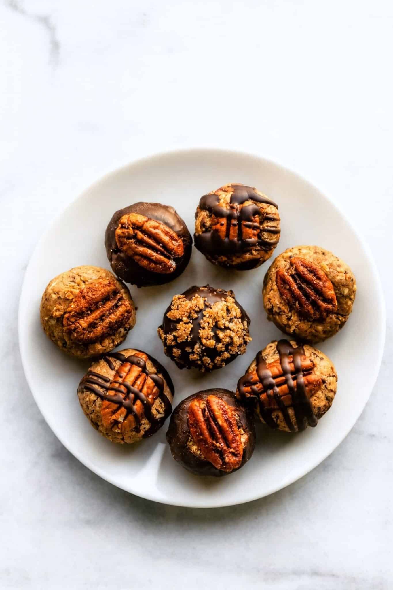 Small no- bake dessert balls drizzled with chocolate and topped with pecans.