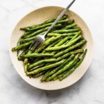 Overhead photo of air fried green beans in a shallow bowl with a fork.