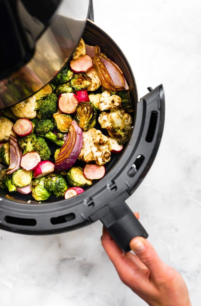 overhead image of air fryer basket filled with mixture of cooked vegetables