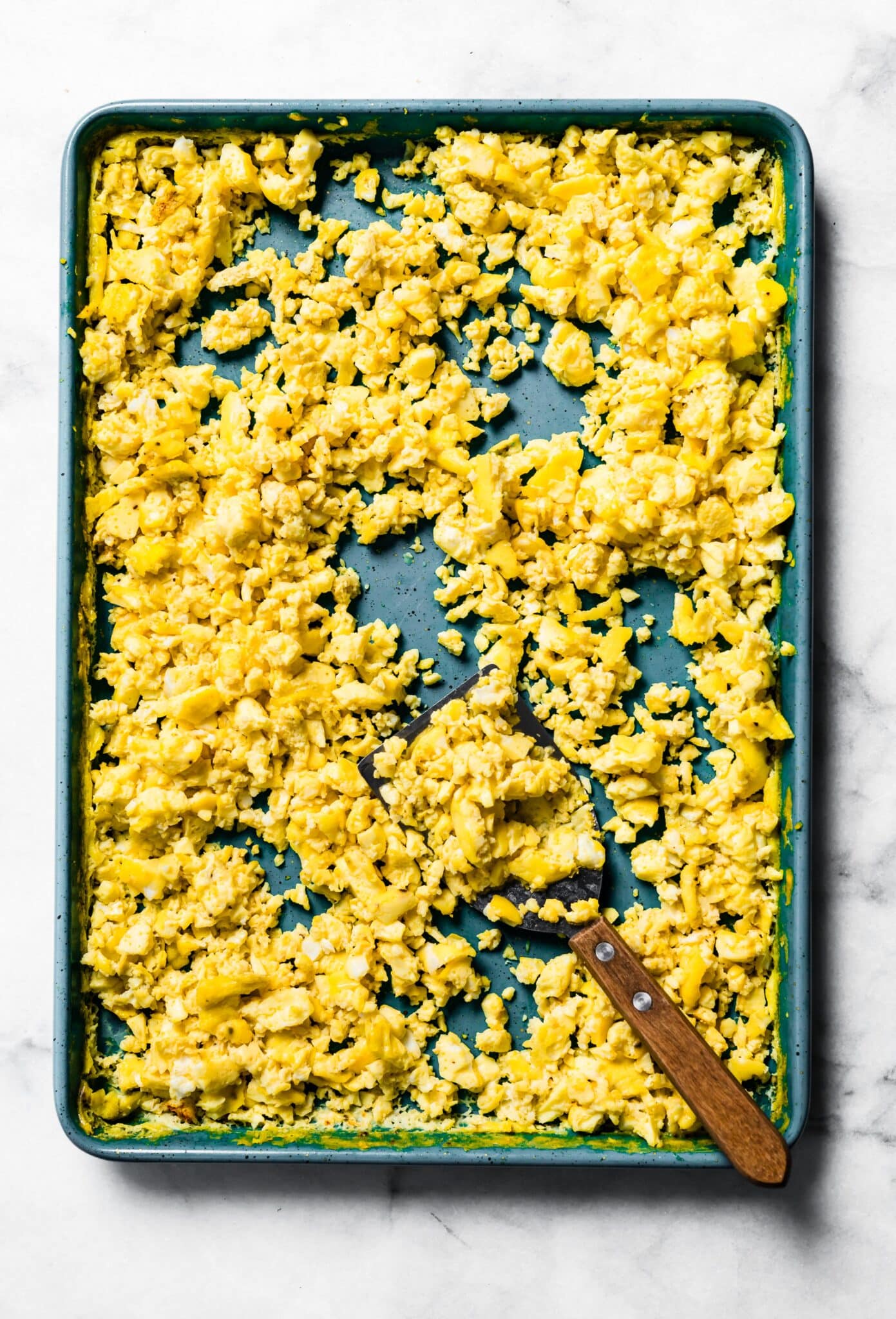 Oven scrambled eggs on a blue sheet pan.