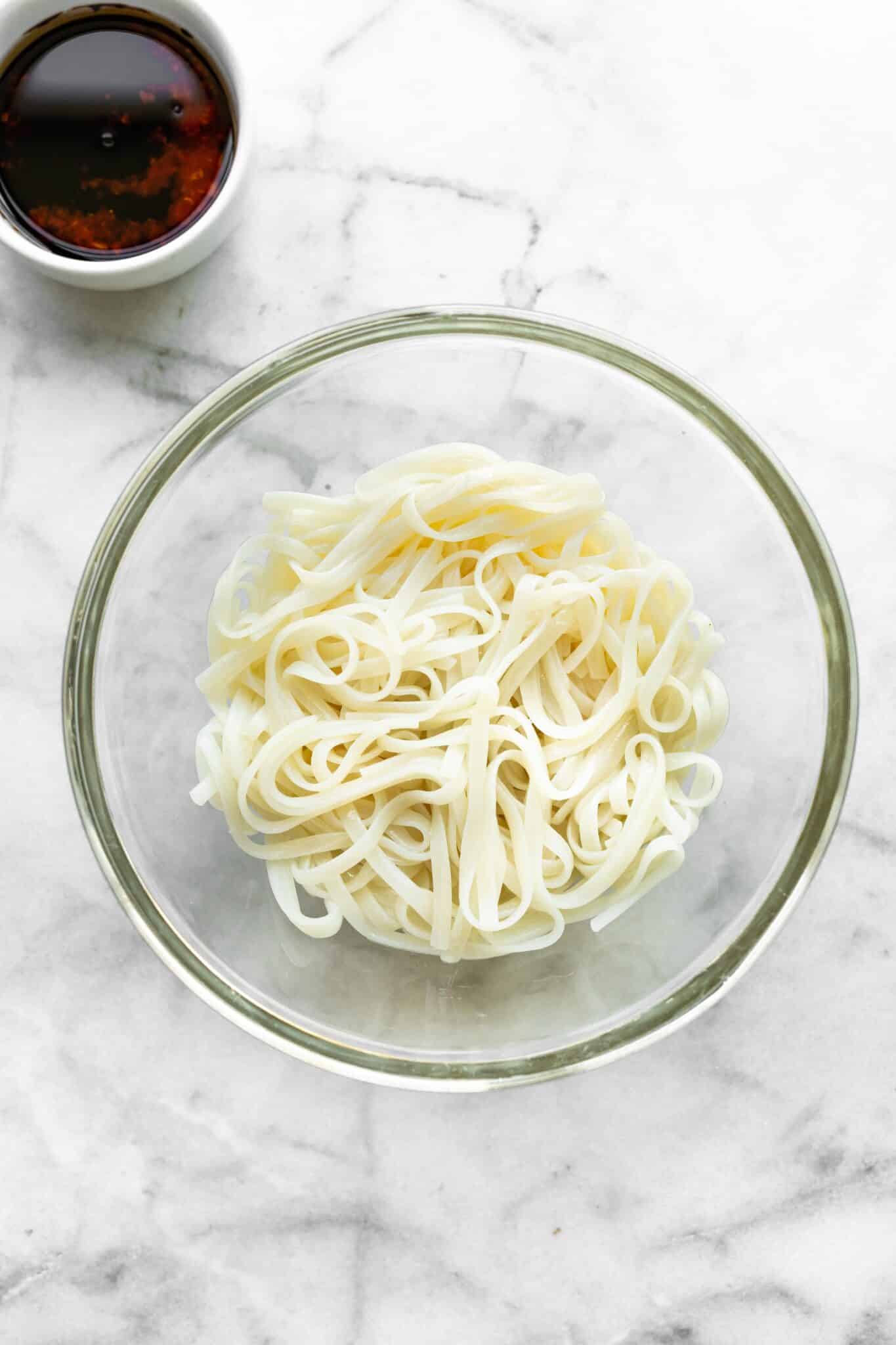 Overhead head photo of cooked rice noodles in a glass bowl.