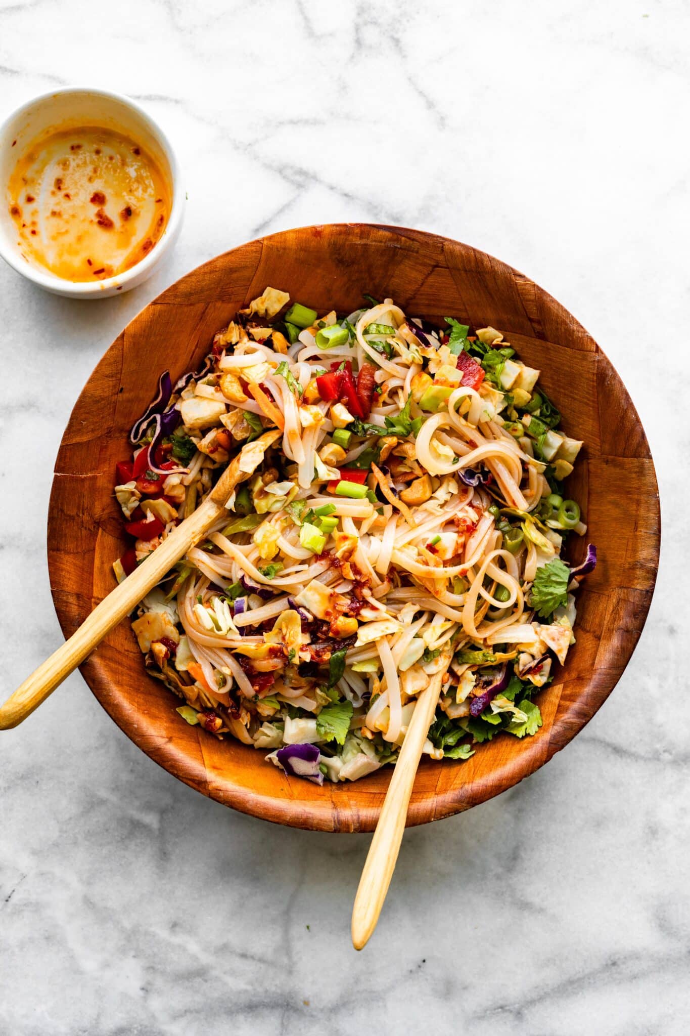 Overhead photo of two wooden spoons mixing a spicy sweet chili sauce into a salad.