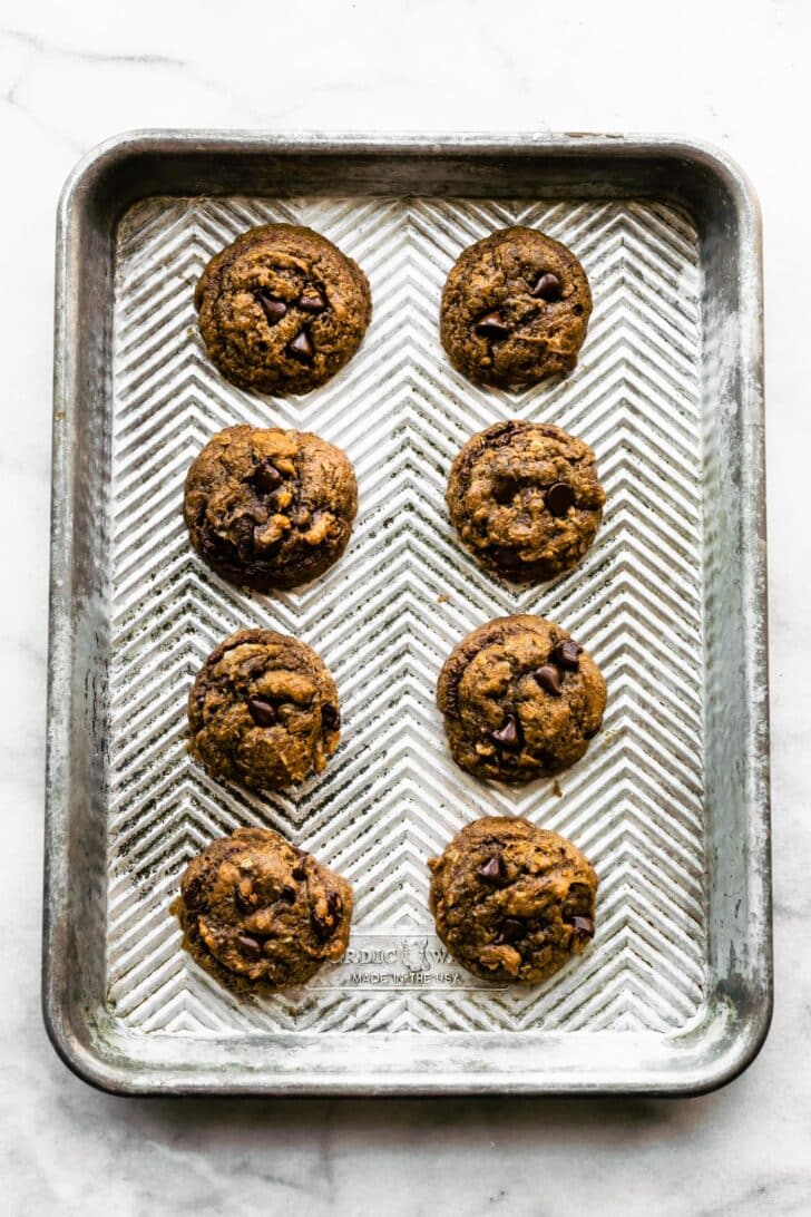 Gluten-free almond butter banana breakfast cookies freshly baked on a silver baking sheet.