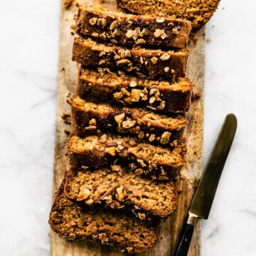 Sliced gluten free apple bread on a wooden cutting board with a knife.