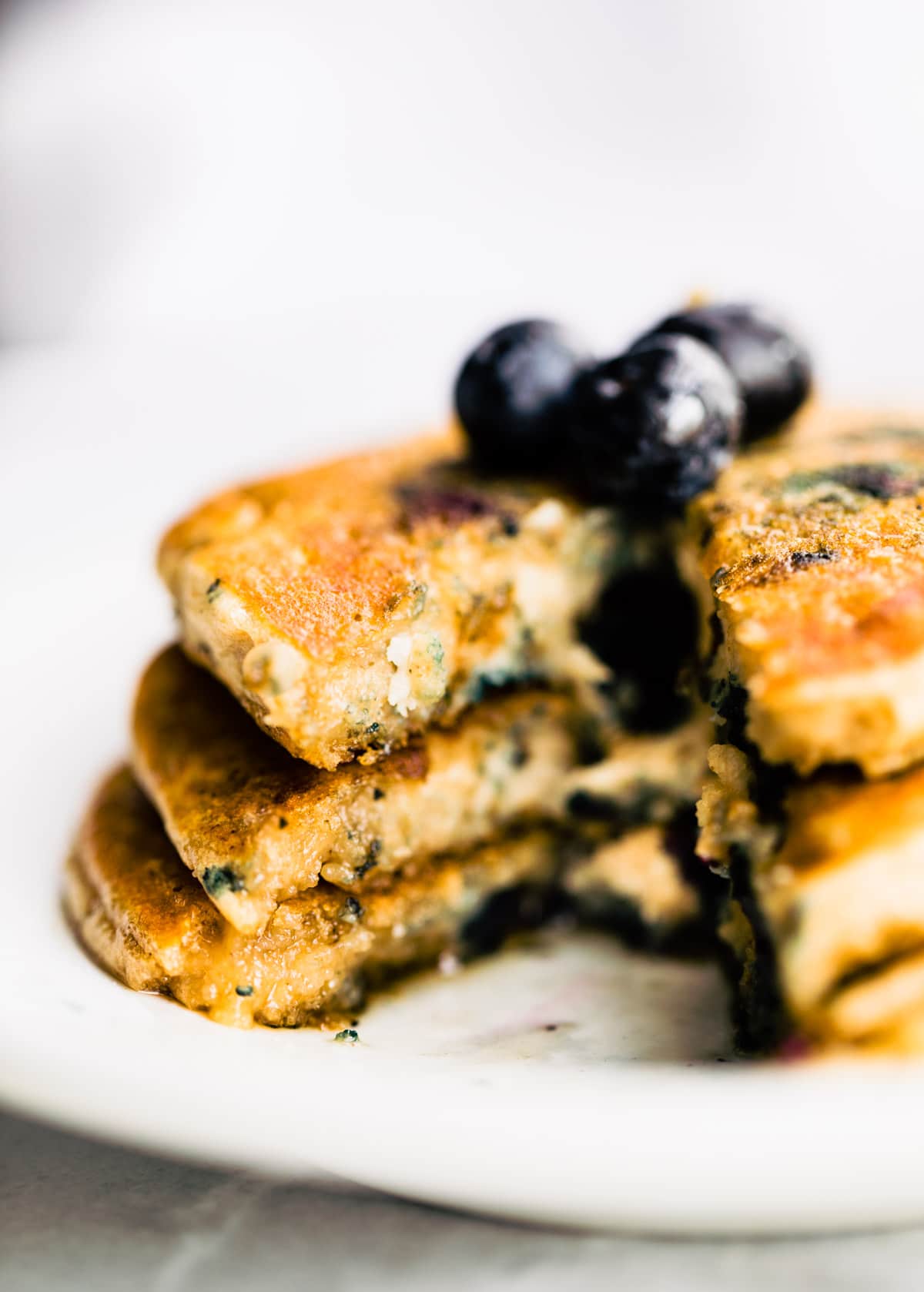 plated stack of fluffy homemade blueberry pancakes with blueberries on top