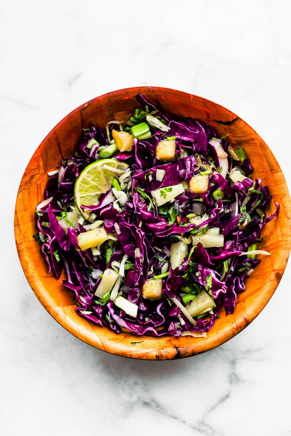 Overhead image of a wood bowl full of pineapple slaw.