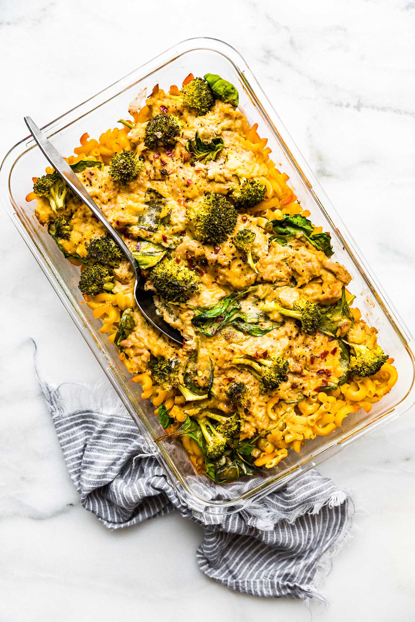 casserole with tuna and pasta and broccoli in a clear glass baking dish.