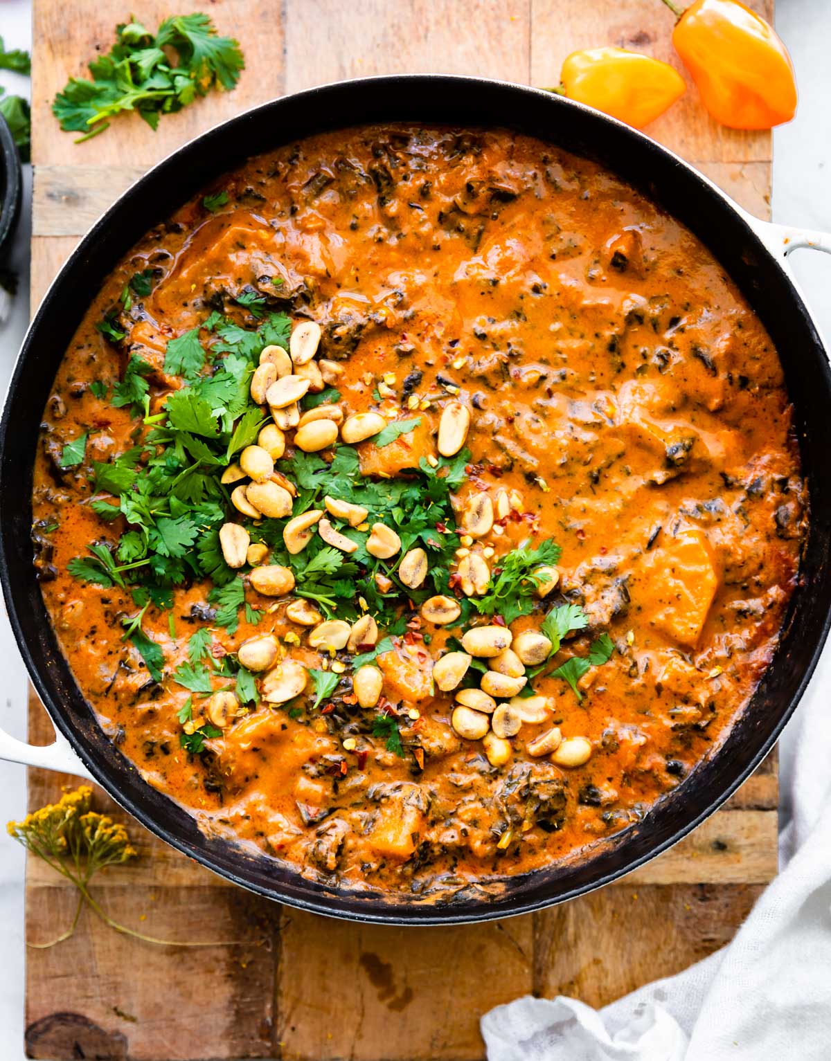 overhead: large pot of spicy stew garnished with peanuts and cilantro