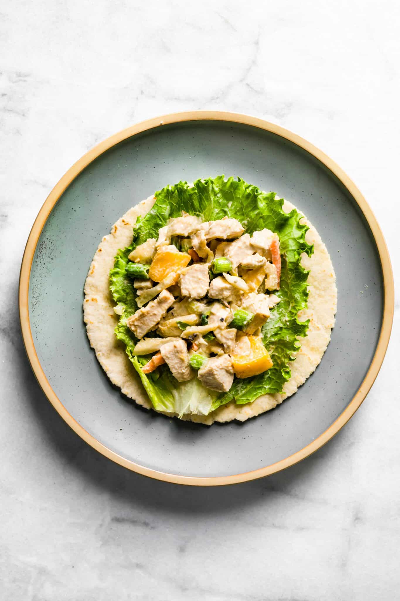 Overhead photo of Asian chicken salad on a lettuce leaf on a gluten free tortilla.