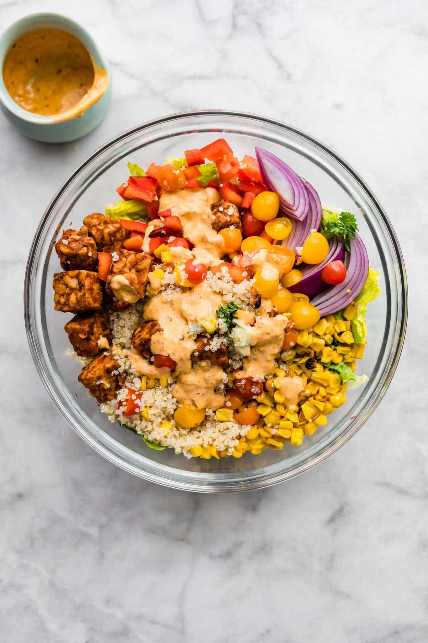 Homemade dressing poured over salad ingredients in a glass bowl.