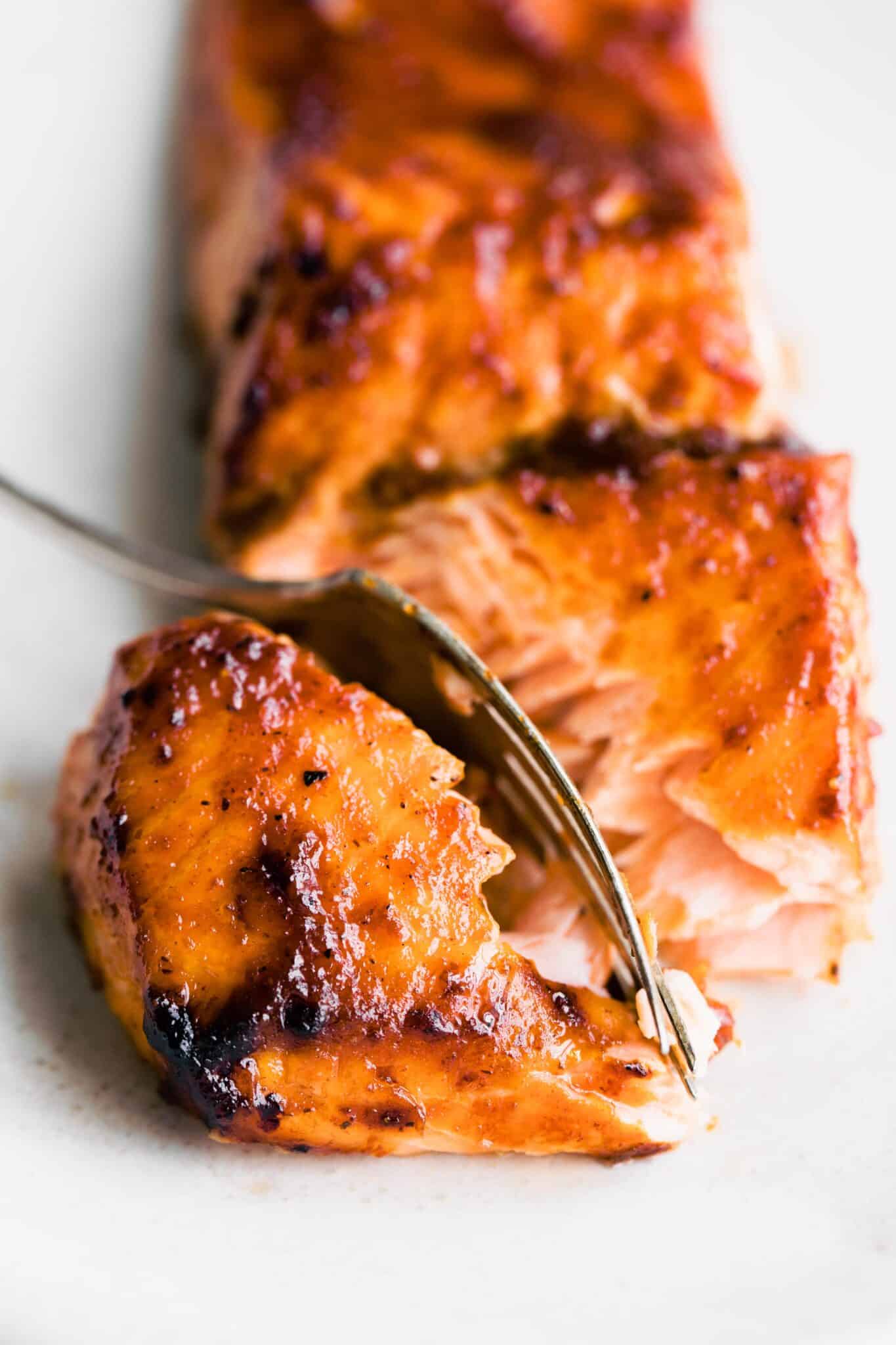 A fork slicing through a piece of barbeque salmon filet.