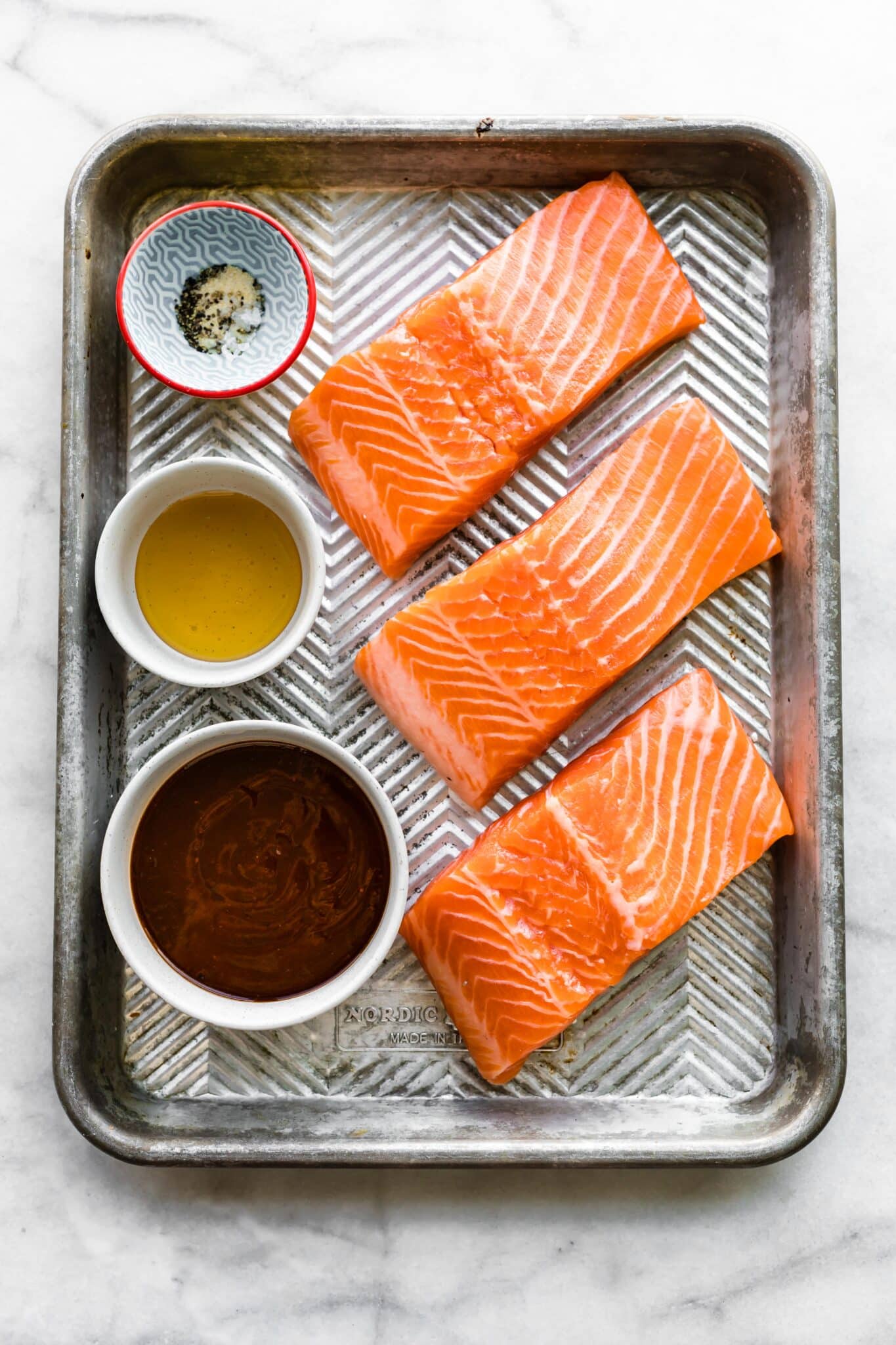 Ingredients for oven baked bbq salmon on a metal sheet pan.