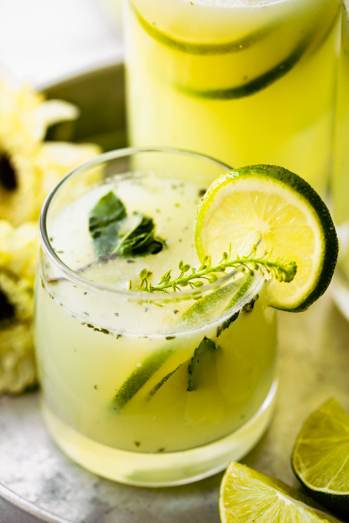 Brazilian limeade in a cocktail glass garnished with slice of lime and fresh herbs.