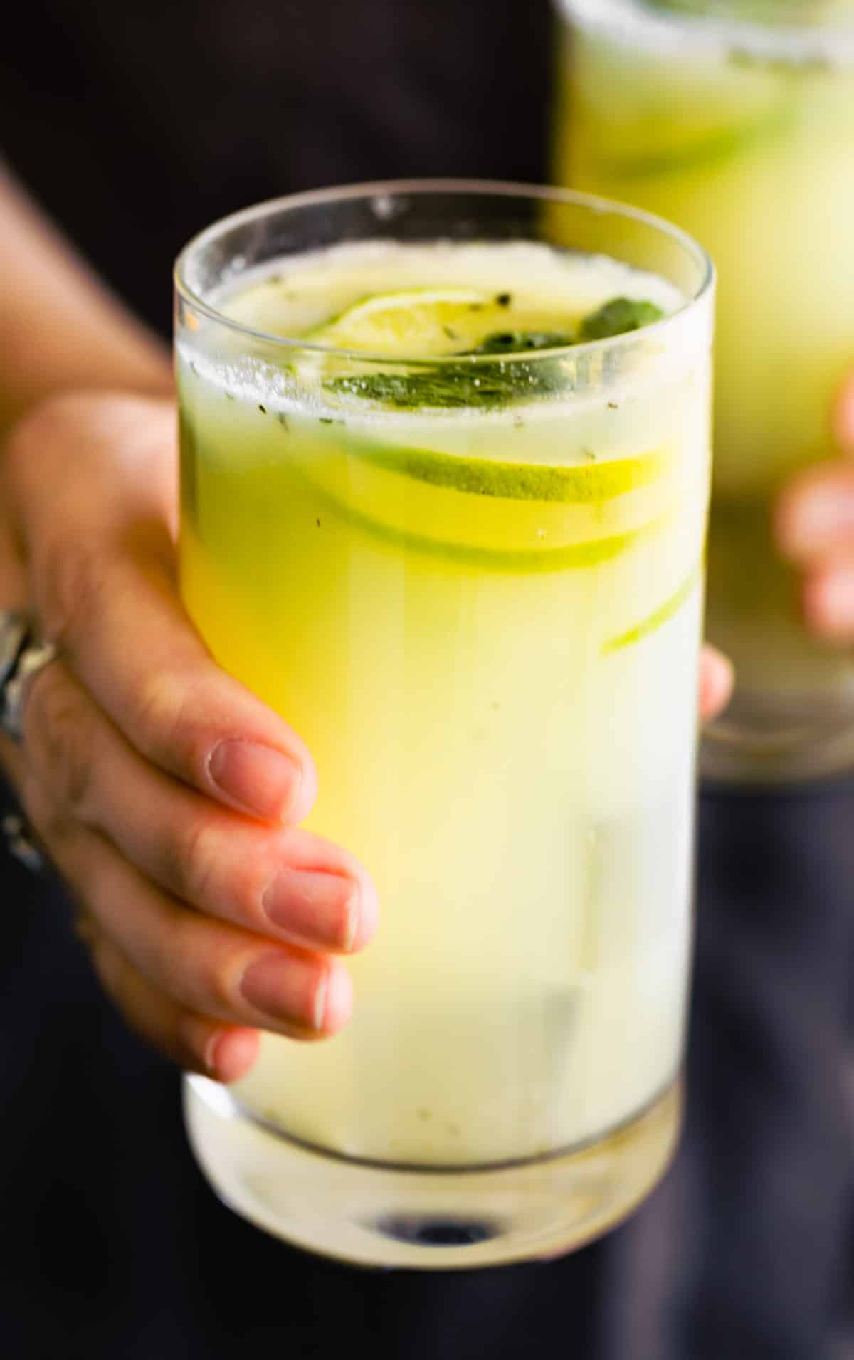 A woman holding a glass of easy Brazilian limeade.
