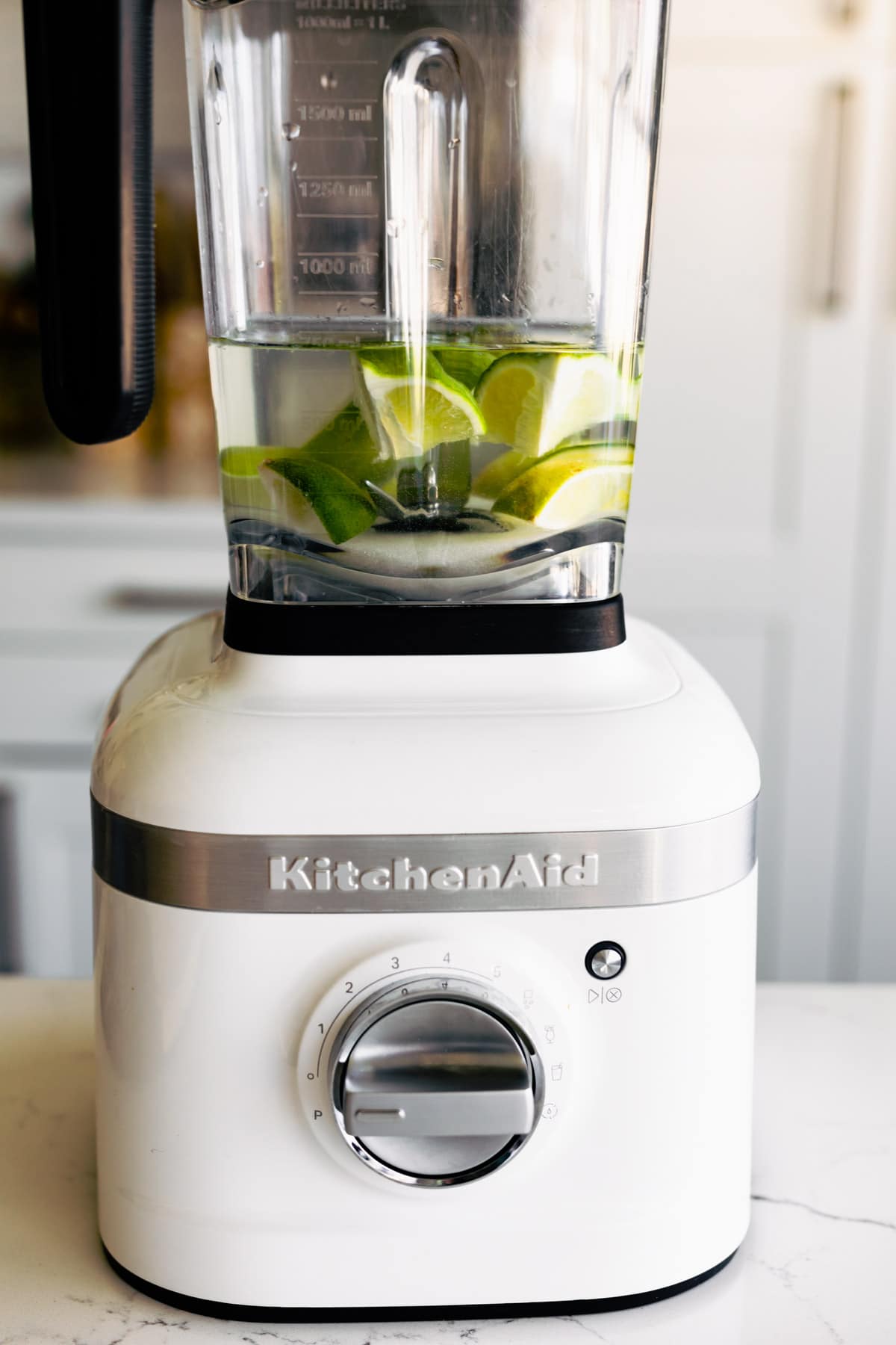 Lime wedges and water in a white KitchenAid blender.