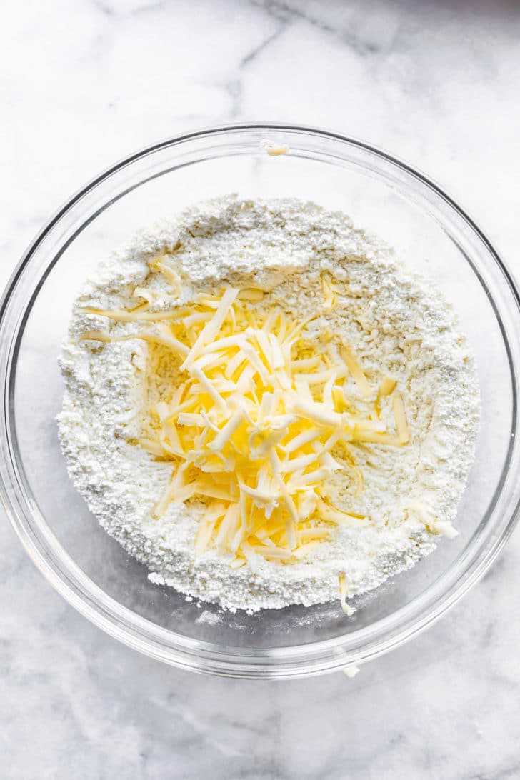 butter being grated into dough for gluten free biscuits