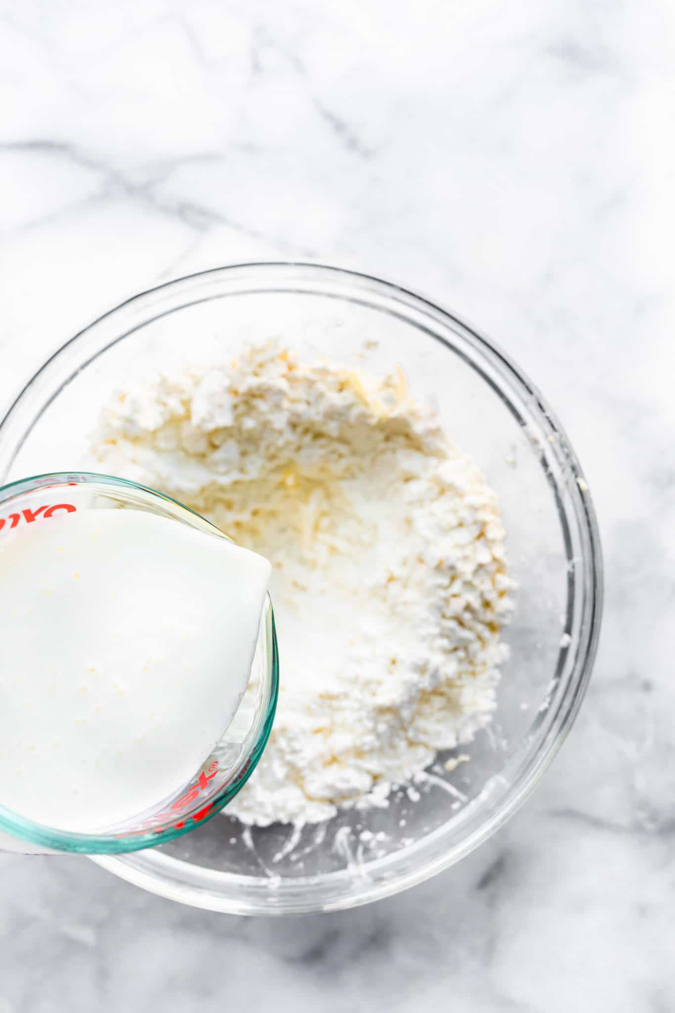 dairy-free milk being poured into dough for gluten free biscuits