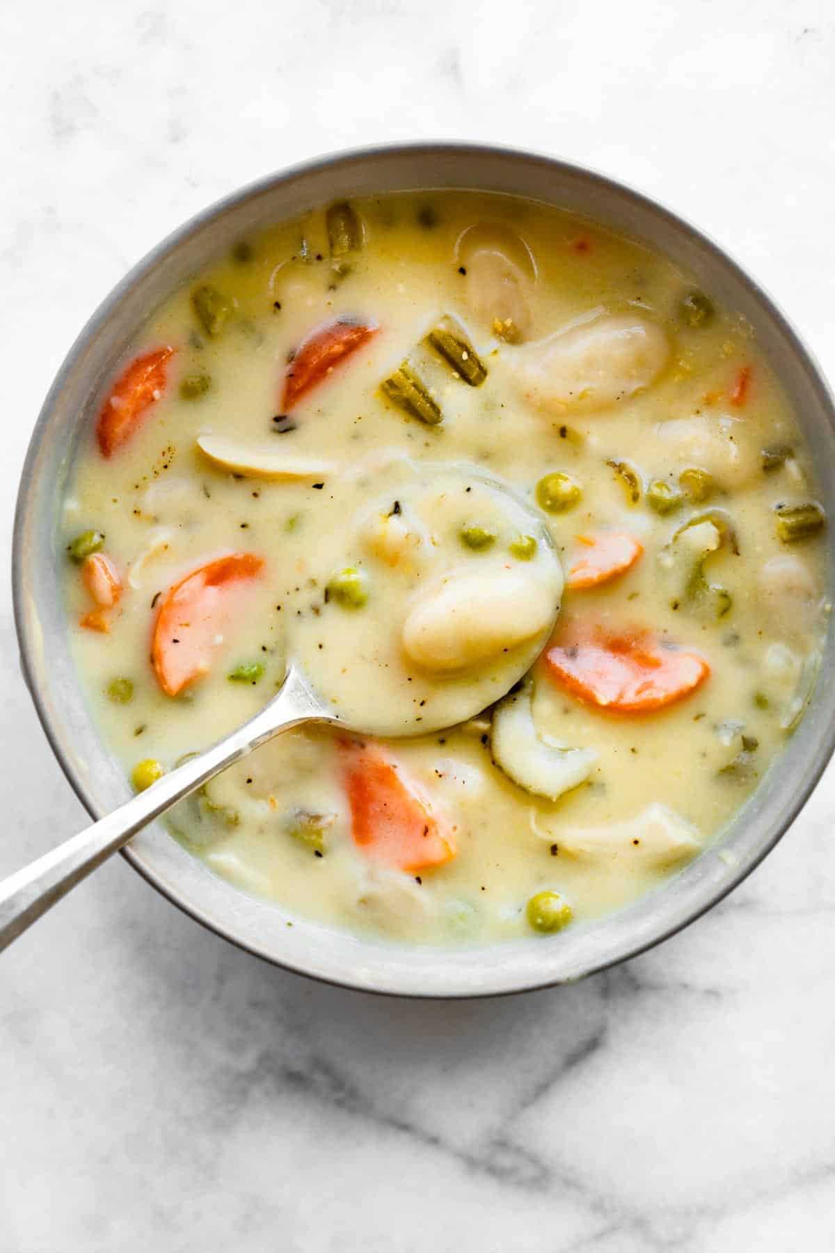 Overhead photo of a spoon in a bowl of gluten free chicken and gnocchi soup.
