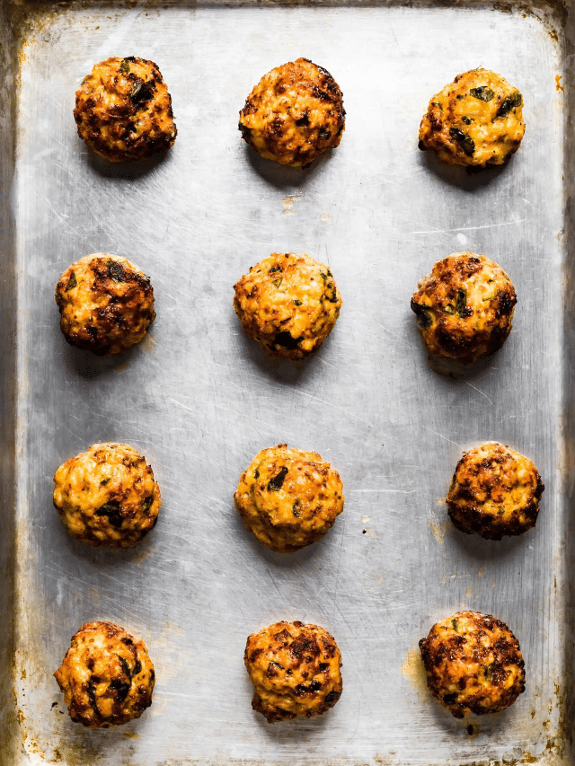 Overhead photo of twelve cooked gluten free chicken meatballs on a sheet pan.