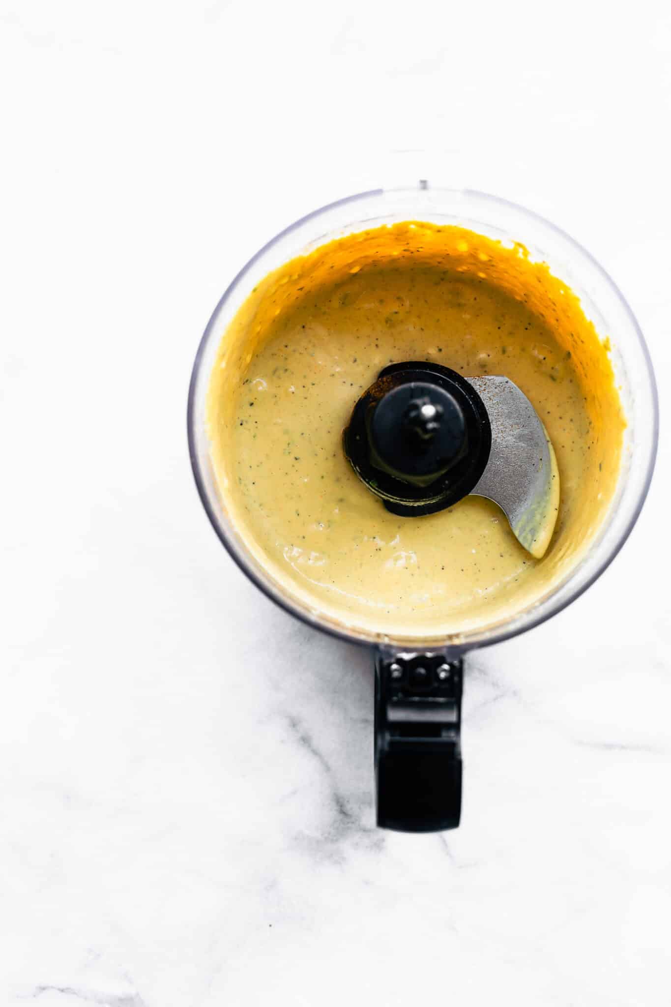Overhead photo of creamy mustard dressing in a food processor.