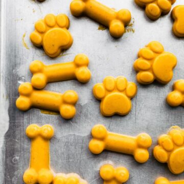 Homemde dog treats shaped as bones and paw prints on a baking sheet