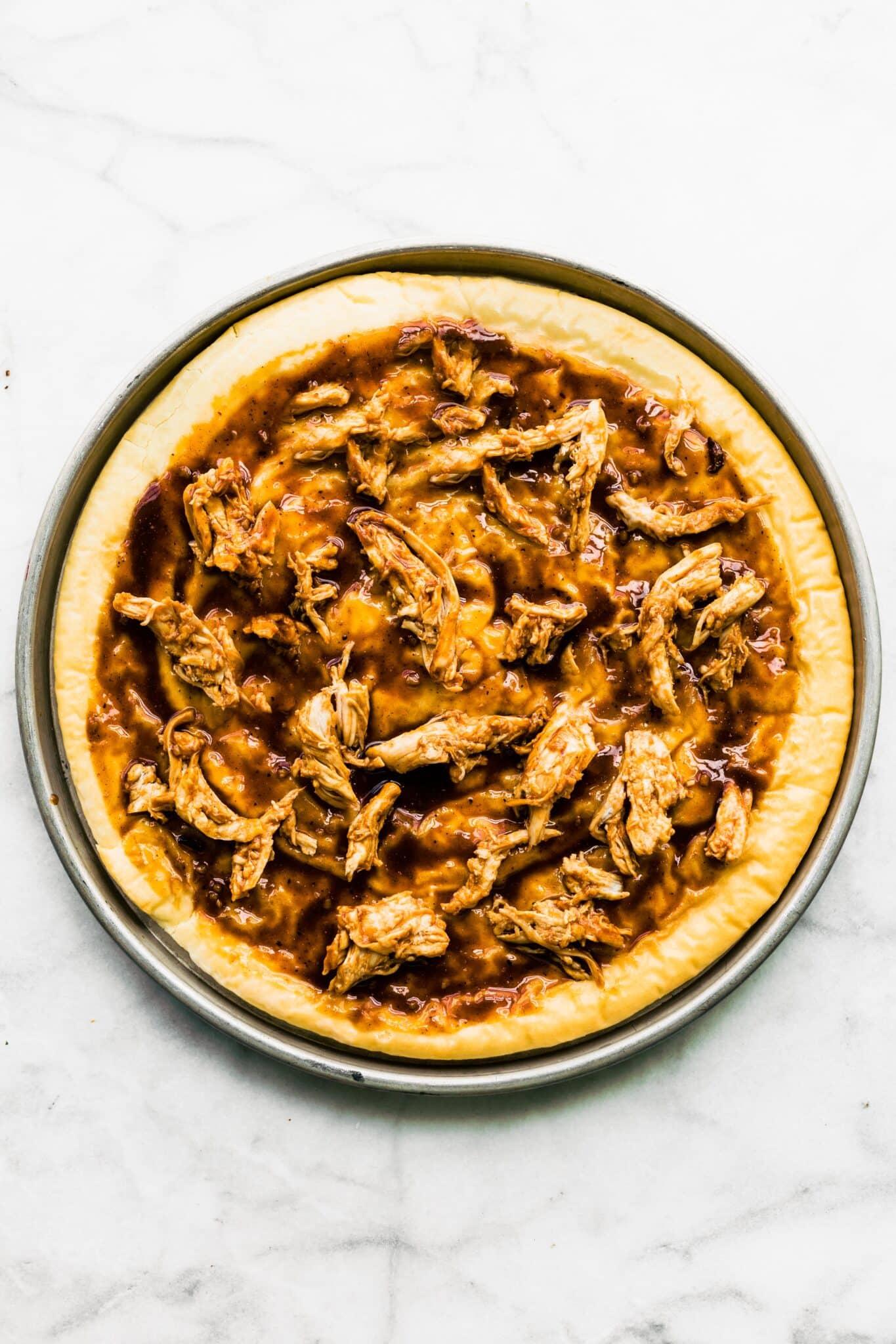 BBQ chicken and BBQ sauce on parbaked gluten free pizza dough.