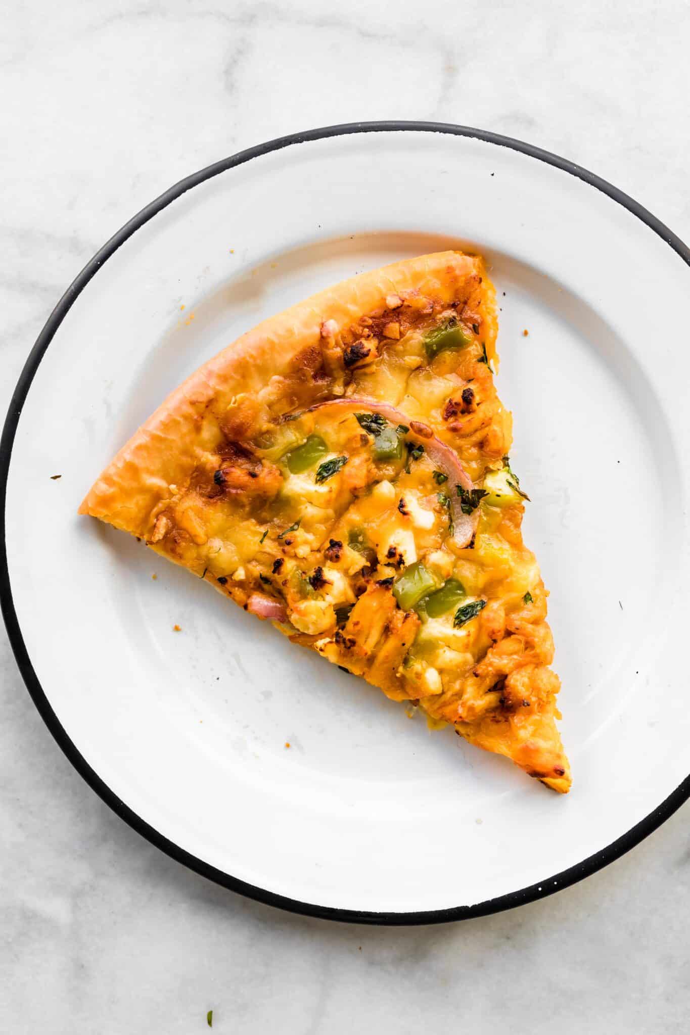 Overhead photo of a slice of BBQ chicken pizza on a white plate.