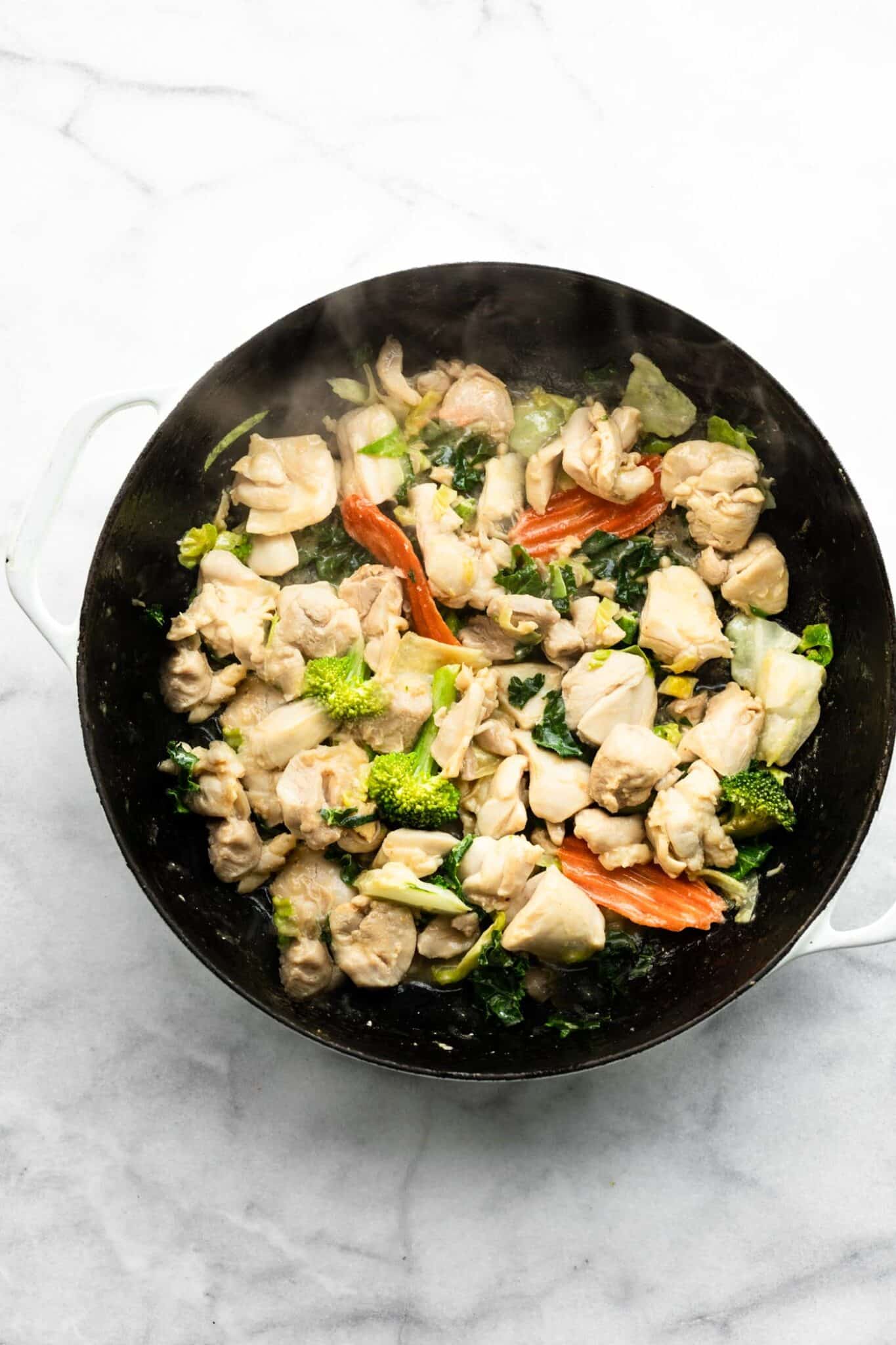 Overhead photo of sauteed veggies and chicken in a cooking pot.