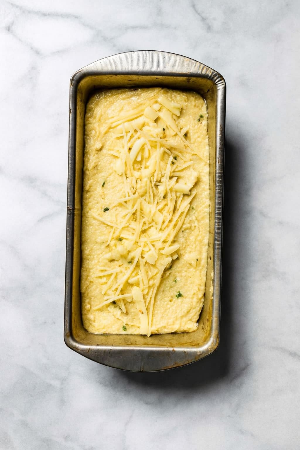 Unbaked gluten free mashed potato bread topped with Parmesan cheese.