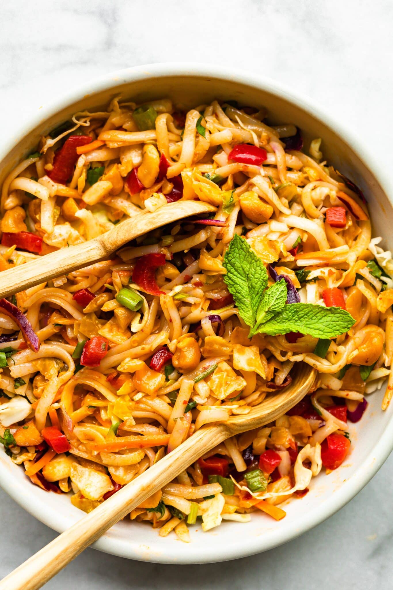 Up close photo of two wooden spoons in a bowl of gluten free Thai noodles.