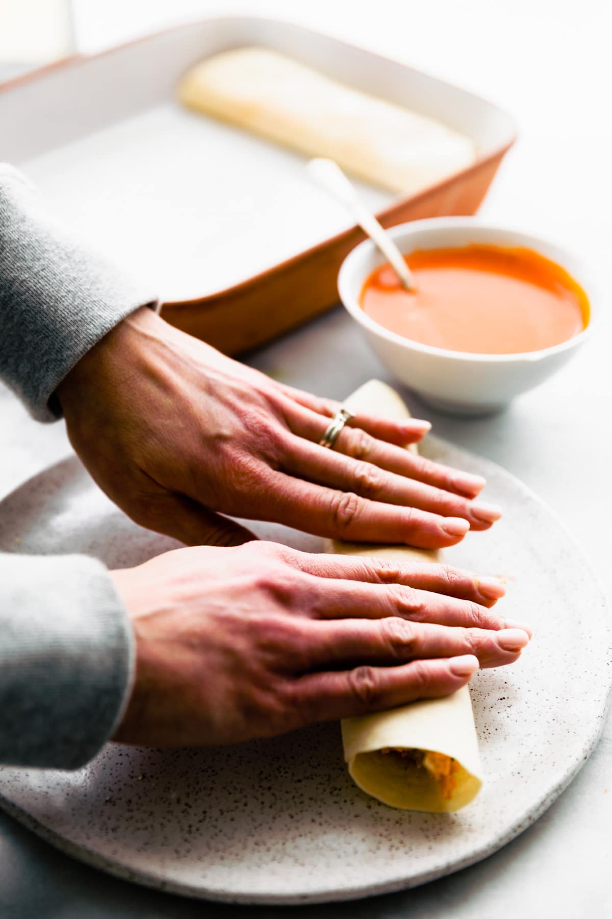 woman's hands rolling gluten free tortillas for enchiladas
