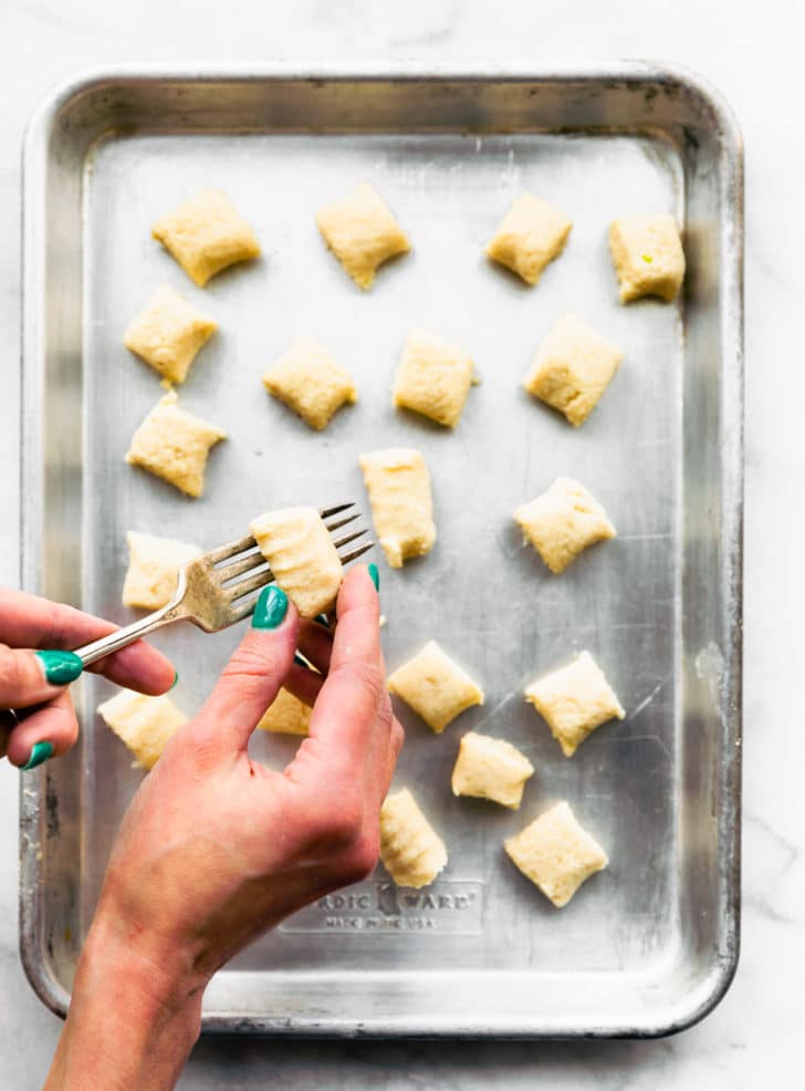 Rolling gnocchi dough on a fork with your hand to shape it.