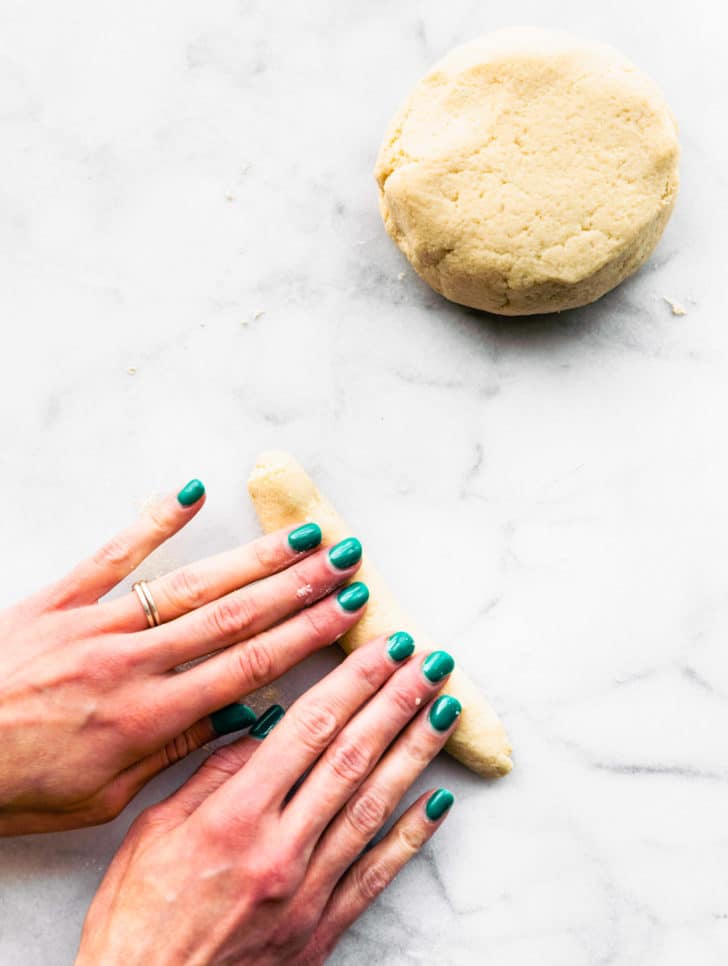 A woman's hands rolling a piece of dough for homemade gnocchi.