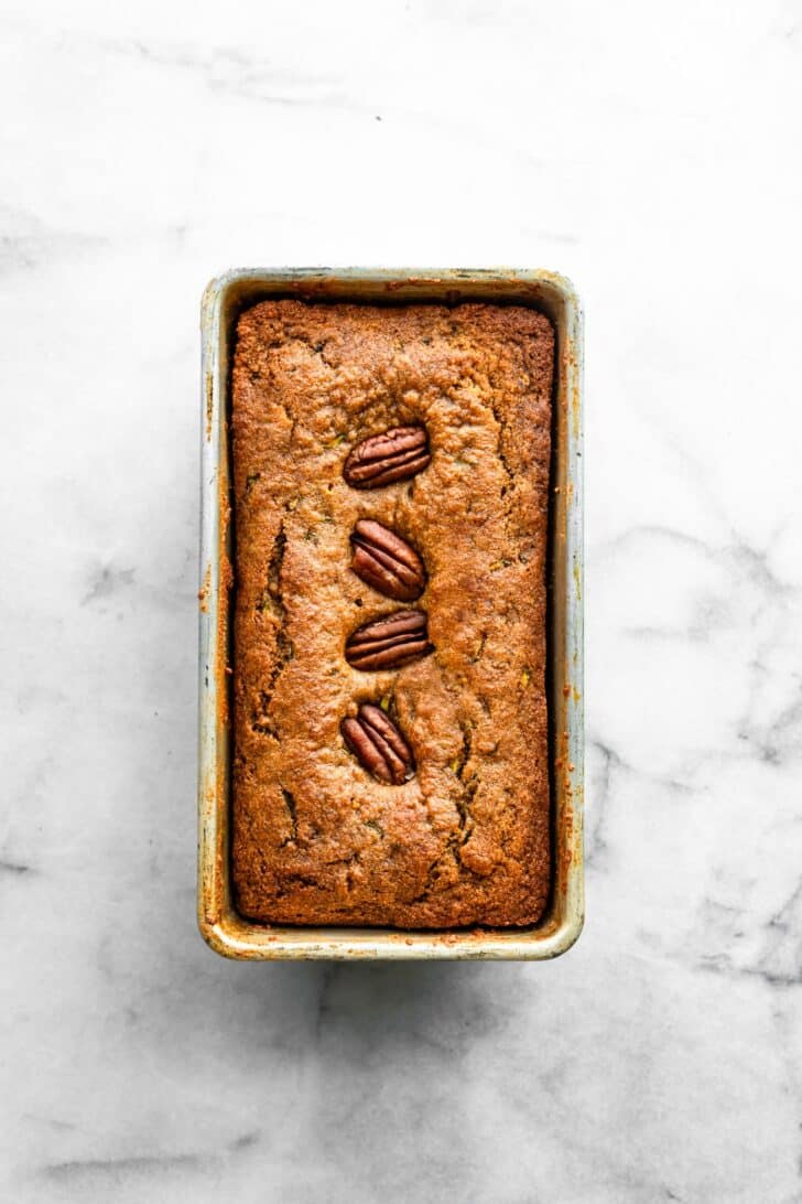 overhead photo of baked zucchini bread with walnuts in a baking pan