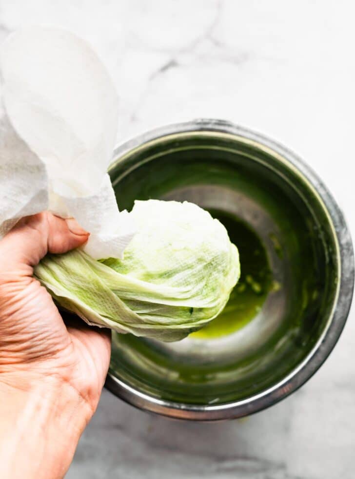 woman's hand squeezing a towel of grated zucchini into a metal bowl