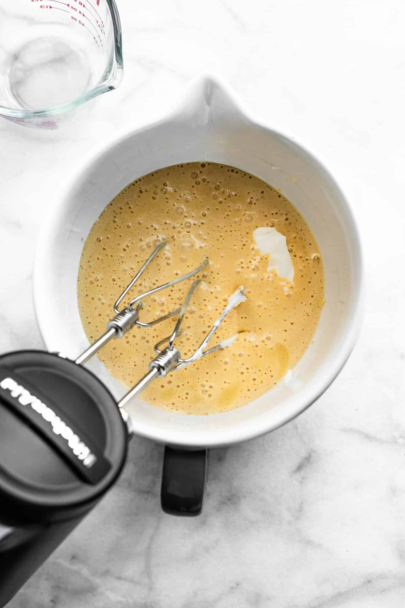 Mixing yogurt into wet ingredients in a mixing bowl.