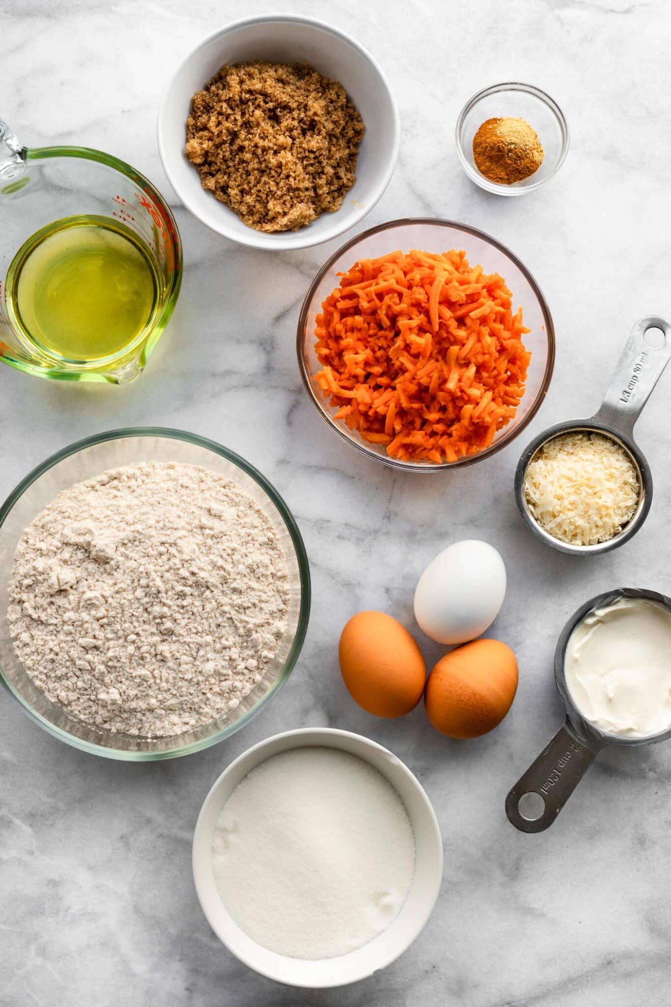 Ingredients for gluten free carrot cake on a white marble countertop.