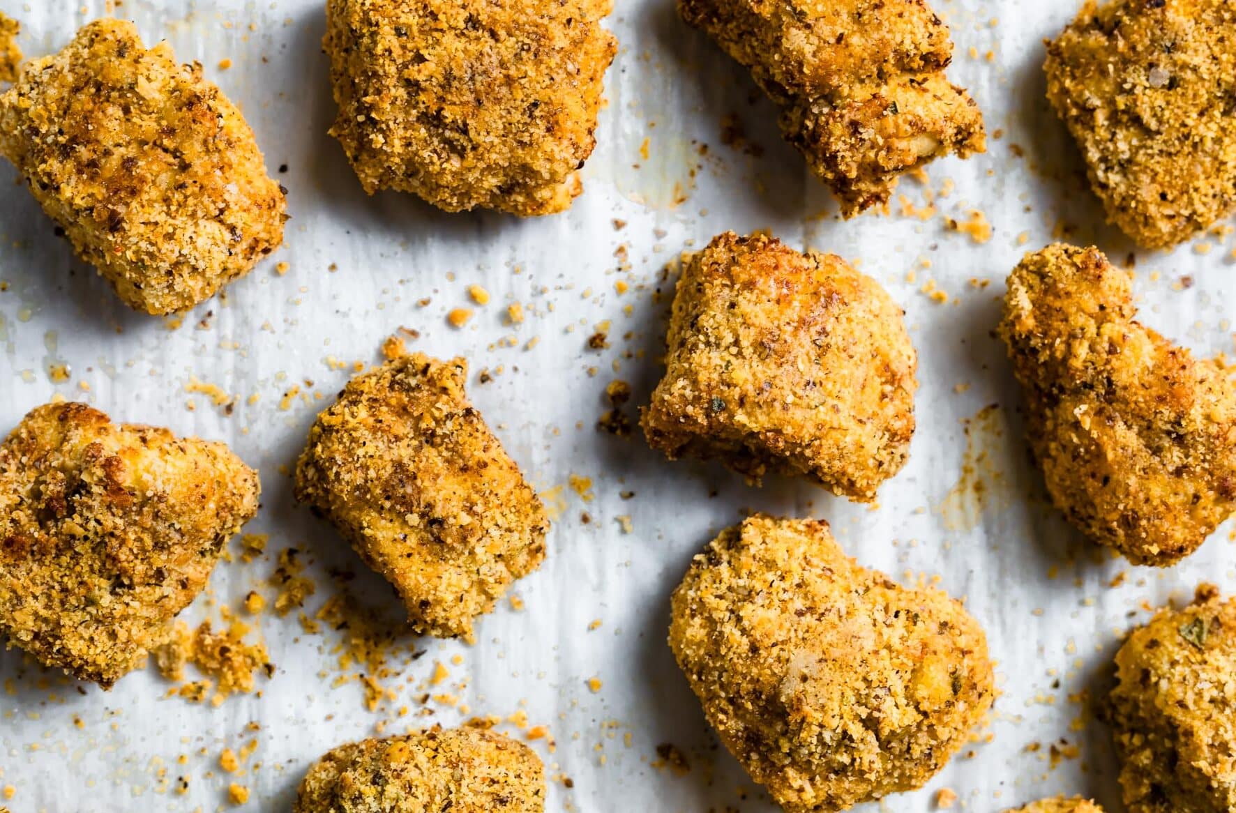 Baked gluten-free chicken nuggets on a parchment-lined tray, golden and crispy.