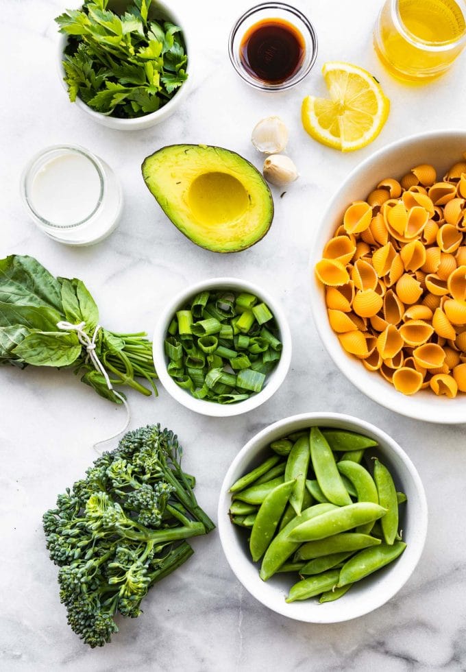 Ingredients for Green Goddess Pasta Salad in bowls on a white countertop.