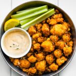Overhead photo of vegan buffalo cauliflower in a serving dish with celery and dip.