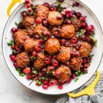 slow cooker gluten free meatballs with cranberry sauce on a serving dish topped with extra cranberries