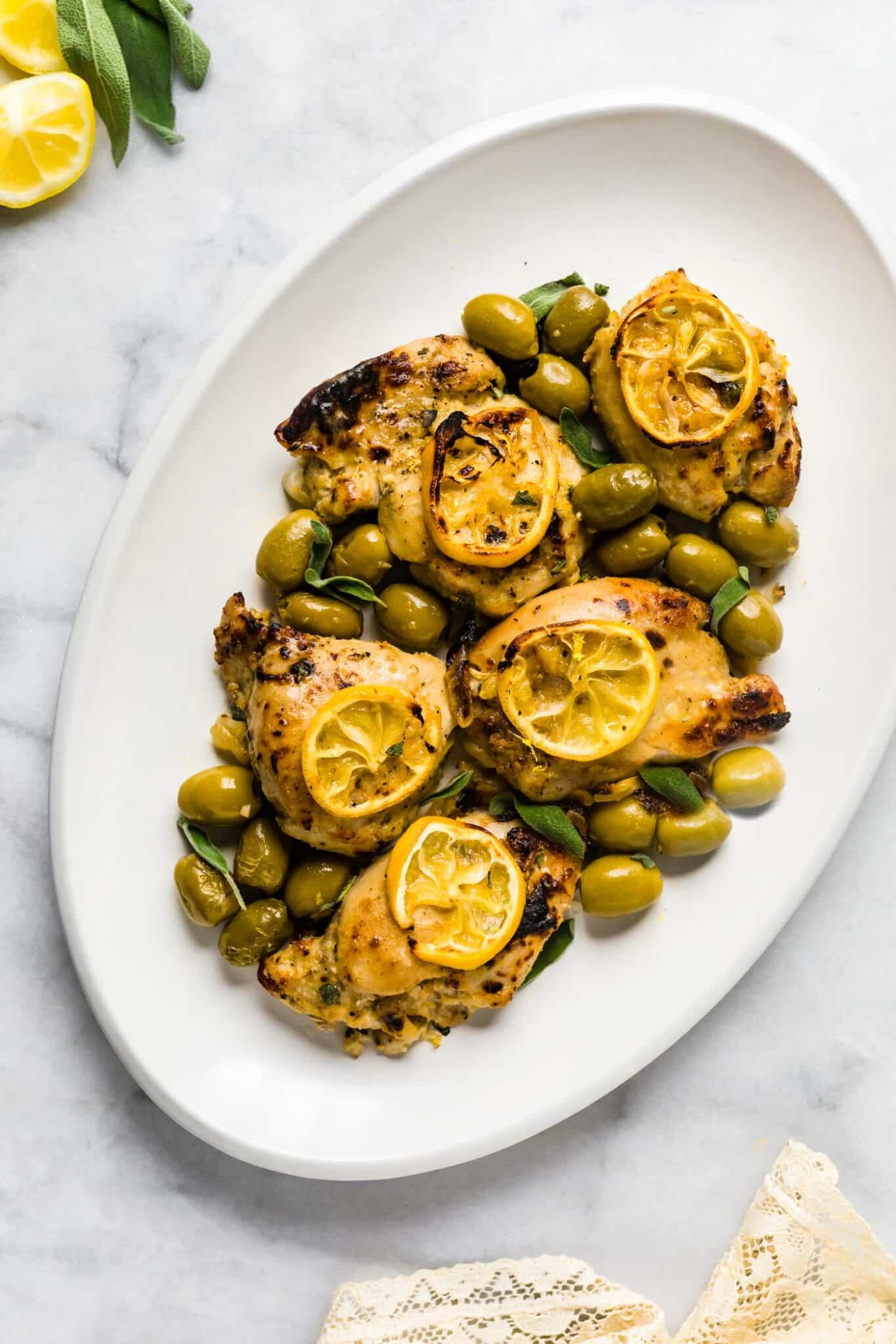 Sage chicken thighs topped with roasted lemon slices and green olives.
