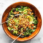 brown bowl of Moroccan salad with quinoa with serving utensils nestled in the salad