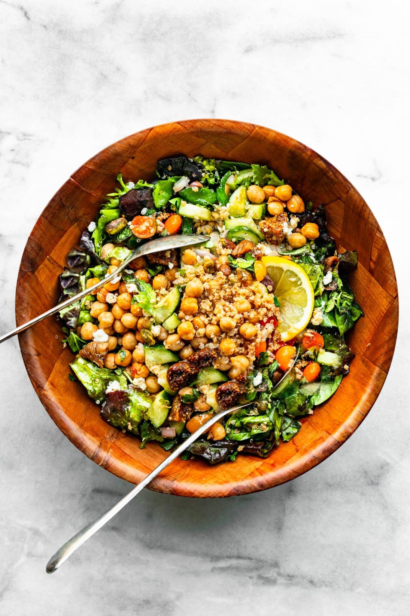 brown bowl of Moroccan salad with quinoa with serving utensils nestled in the salad