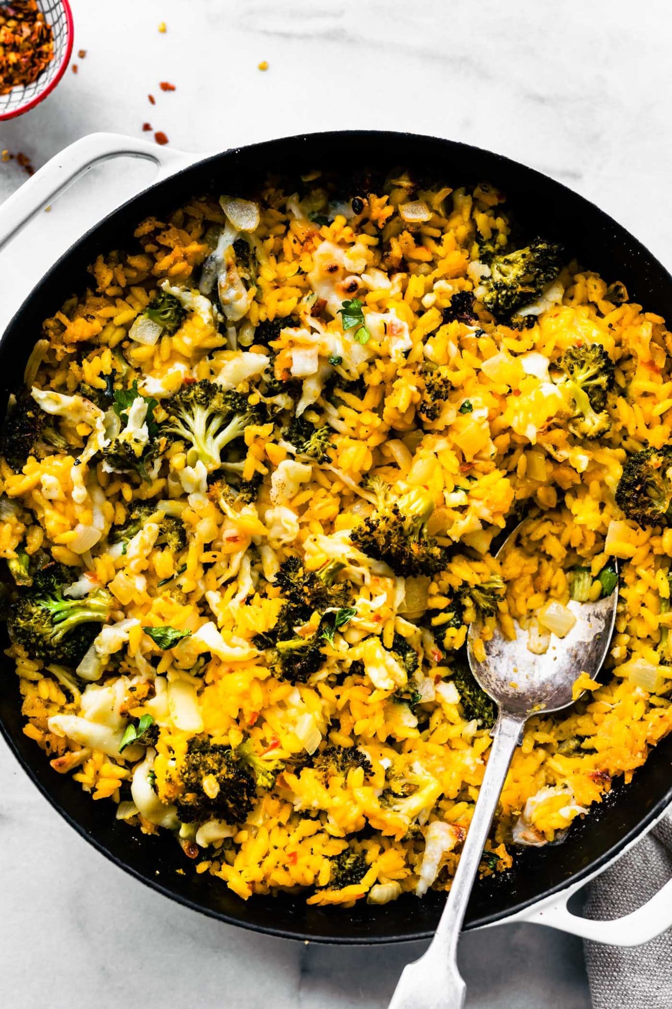 healthy broccoli and cheese casserole in a pan being scooped with a spoon