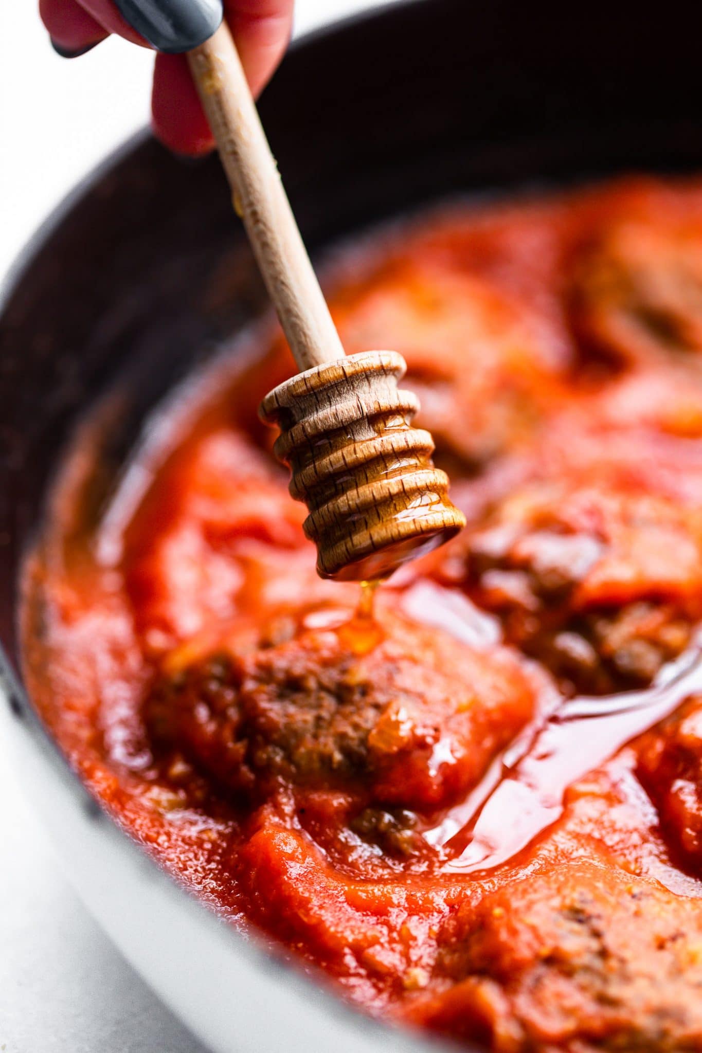Close up of honey being drizzled into meatballs and sauce with honey dipping.