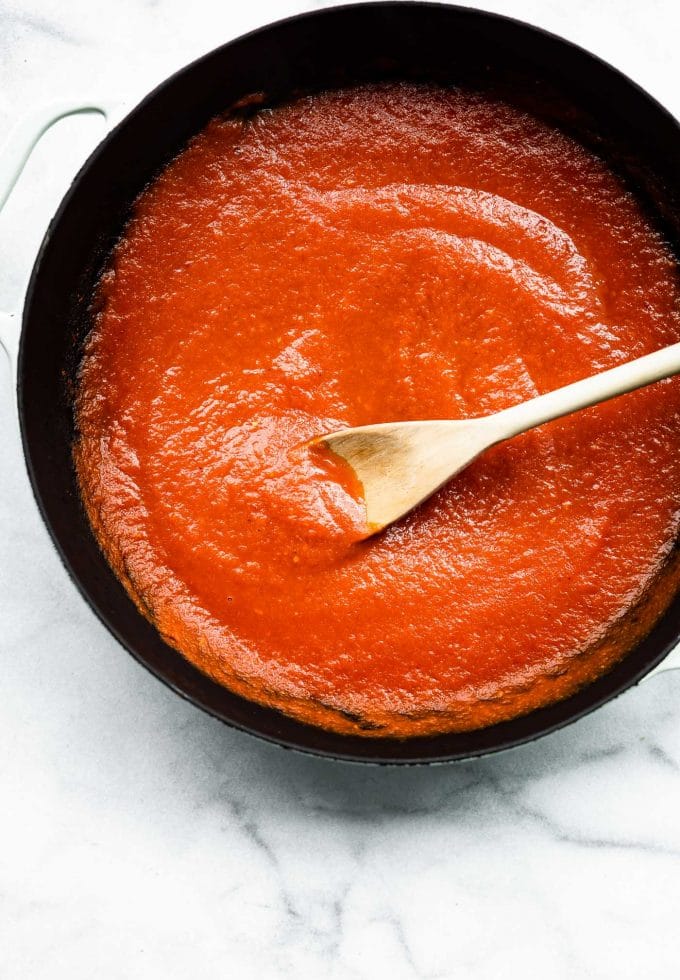 Overhead view skillet with honey sriracha meatballs sauce with wooden spoon in sauce.