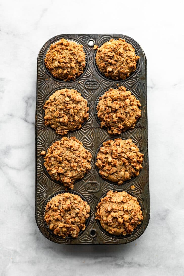 Overhead photo of eight baked honey ricotta muffins in a vintage muffin pan.