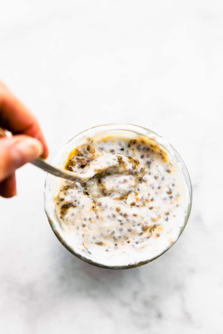 overhead image of a woman's hand stirring up chia pudding with protein
