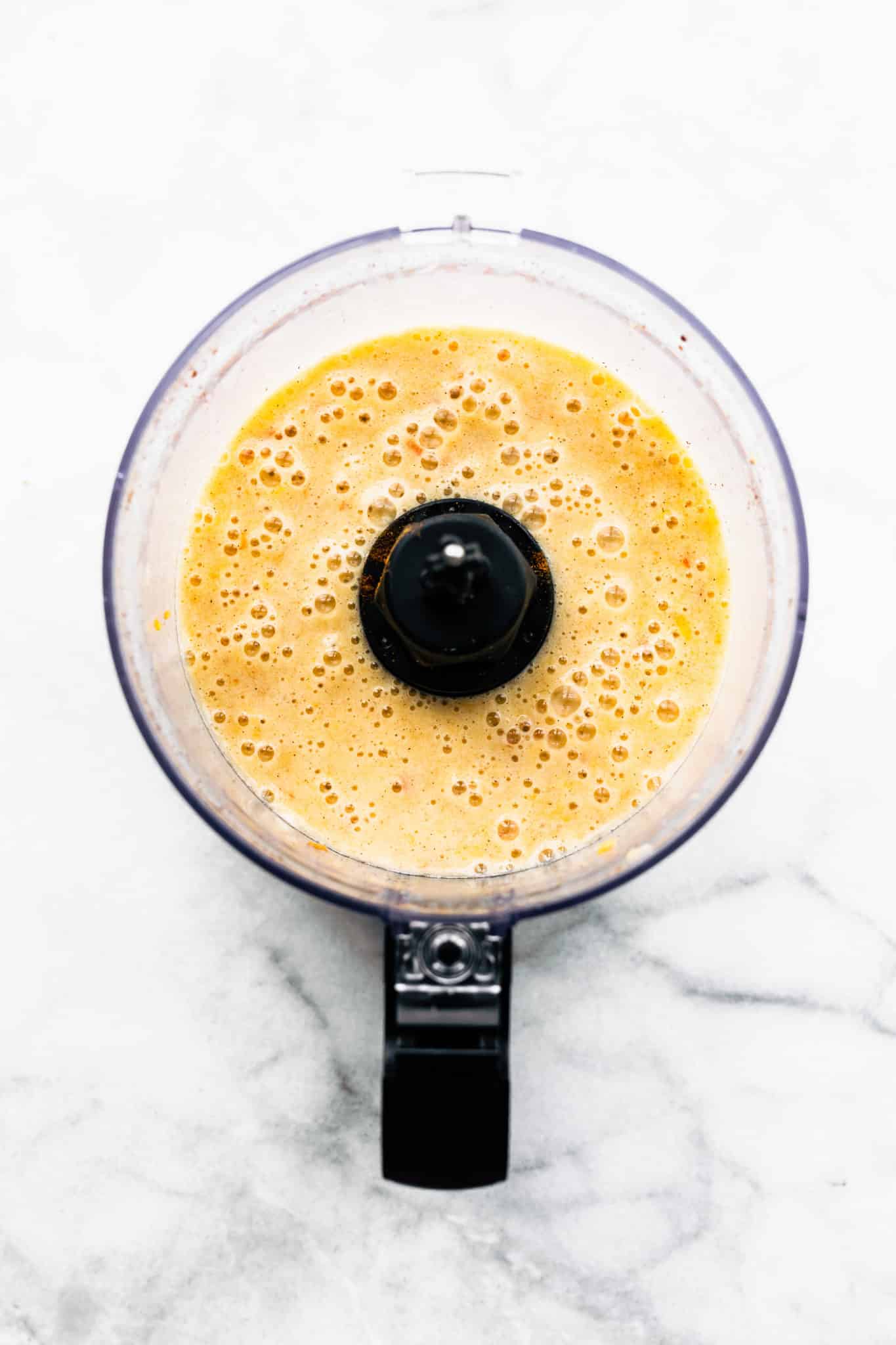 overhead image of blended bananas and peaches with dairy-free milk in a food processor